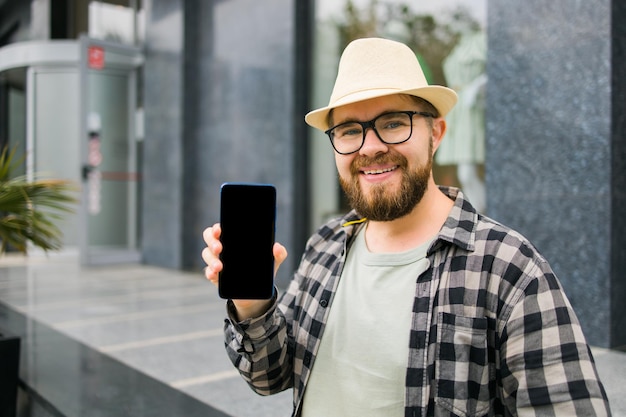 Gorąca oferta Szczęśliwy facet trzyma telefon komórkowy z czarną przestrzenią na kopię i uśmiechniętymi Ludzkimi emocjami na twarzy i miejscem na reklamę i tekst