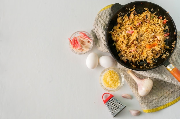Gorąca pasta carbonaro na patelni z przyprawami i składnikami na blacie stołu, przepis na jedzenie