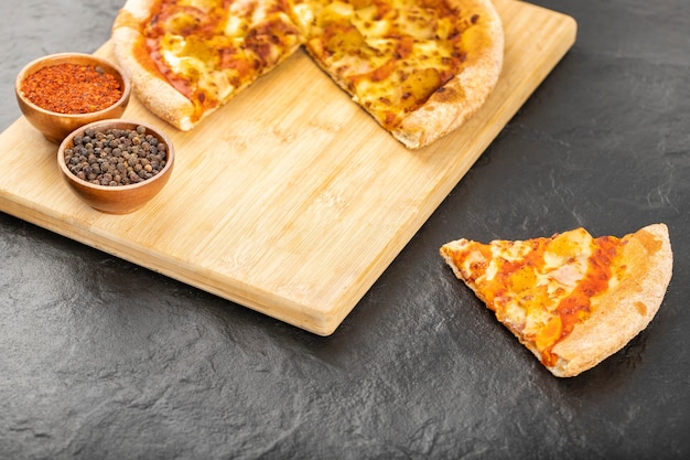 Gorąca pizza pyszna z przyprawami umieszczona na czarnym tle.