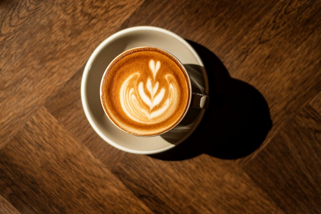 gorący cappuccino z latte sztuki na tle drewna