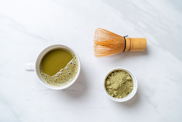 Zdjęcie gorący kubek zielonej herbaty matcha z proszkiem zielonej herbaty i trzepaczką