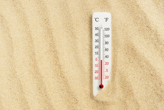 Zdjęcie gorący letni dzień termometr w skali celsjusza i fahrenheita w piasku temperatura otoczenia plus 1