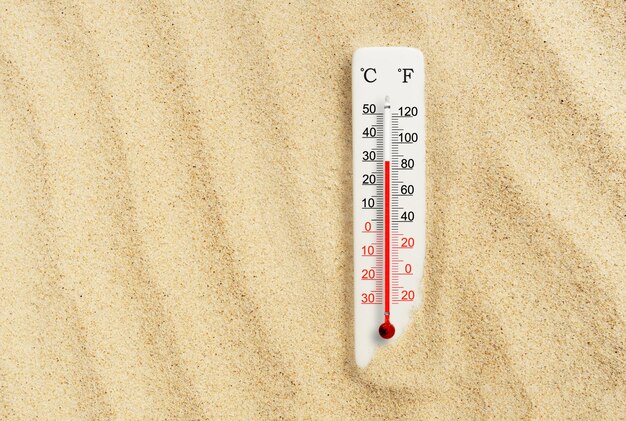 Zdjęcie gorący letni dzień termometr w skali celsjusza i fahrenheita w piasku temperatura otoczenia plus 30