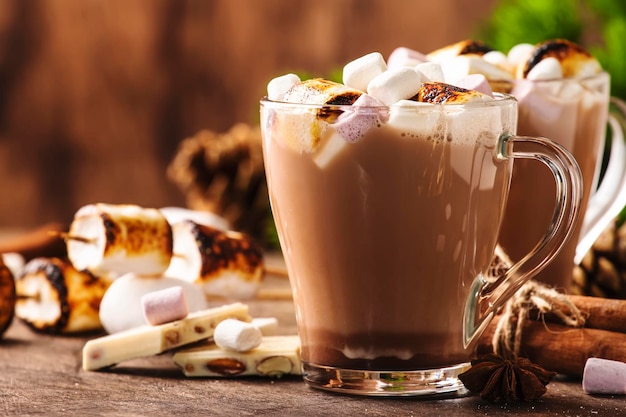 Gorący napój kakaowy lub czekoladowy z pianką marshmallow w szklanym kubku i zimowej dekoracji na drewnianym stole Koncepcja przytulnej przestrzeni kopii świąt Bożego Narodzenia i Nowego Roku