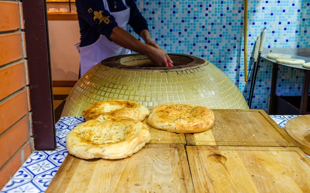 Gorący okrągły chleb pita leży na stole w pobliżu piekarnika.