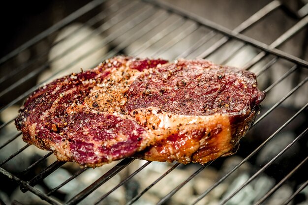 Gorący pikantny stek grillowany na letnim grillu nad rozżarzonymi węglami. Gotowanie żywności. zbliżenie