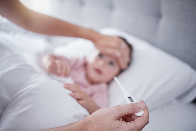 Gorączka rąk i dziecko ręką matki mierzącą temperaturę termometrem chorej córce w łóżku w domu Rodzic mierzący lub badający objawy swojej córeczki w sypialni
