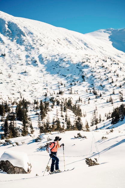 Góral backcountry ski walking skialpinista w górach Skialpinizm w alpejskim krajobrazie z ośnieżonymi drzewami Przygoda sporty zimowe