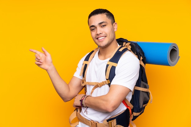 Góral młody człowiek z dużym plecakiem na żółty palec wskazujący z boku