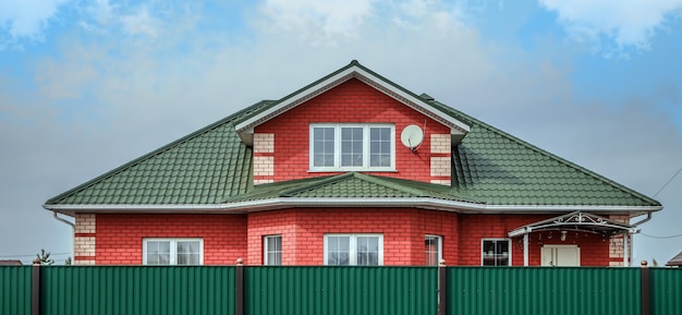 Górna część dachu bardzo zadbanego i kolorowego domu Dach domu z metalowego profilu na tle nieba
