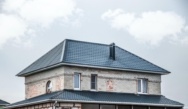 Zdjęcie górna część dachu bardzo zadbanego i kolorowego domu dach domu z metalowego profilu na tle nieba