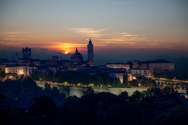 Górne miasto Bergamo o zachodzie słońca na tle gór