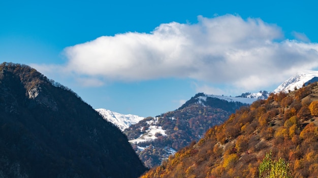 Górski jesienny las i śnieg na szczytach