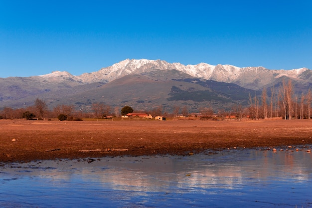 Górski krajobraz ze śniegiem na szczytach odbitym w wodzie jeziora Gredos Mountain