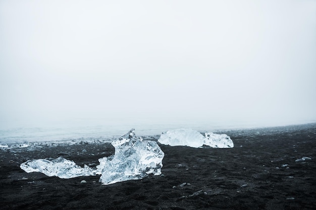 Góry lodowe na plaży z czarnym wulkanicznym piaskiem. Wybrzeże Oceanu Atlantyckiego w pobliżu laguny lodowcowej Jokulsarlon, Południowa Islandia. Selektywne skupienie