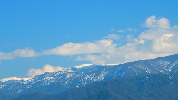 Góry pokryte śniegiem śnieżne szczyty pod niebieskim niebem i poruszające się chmury timelapse