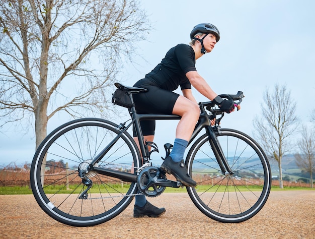 Gotowa jazda na rowerze i fitness z kobietą w przyrodzie do treningu i treningu sportowego cardio Zdrowie, relaks i myślenie z rowerzystką jeżdżącą na rowerze na świeżym powietrzu, aby ćwiczyć wytrzymałość i wyzwanie