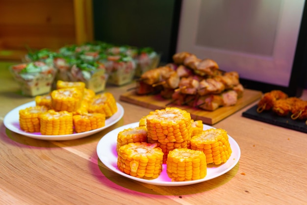 Gotowana kukurydza pokrojona na kawałki na białych talerzach na drewnianym stole Tabela pełna przekąsek Selektywna ostrość