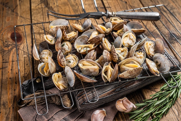 Gotowane muszle Małże, vongole na grillu z czosnkiem i rozmarynem. Drewniane tło. Widok z góry.