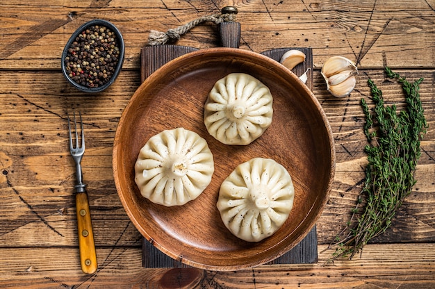 Gotowane pierogi chinkali z jagnięciną baranią na drewnianym talerzu. Drewniany stół. Widok z góry.