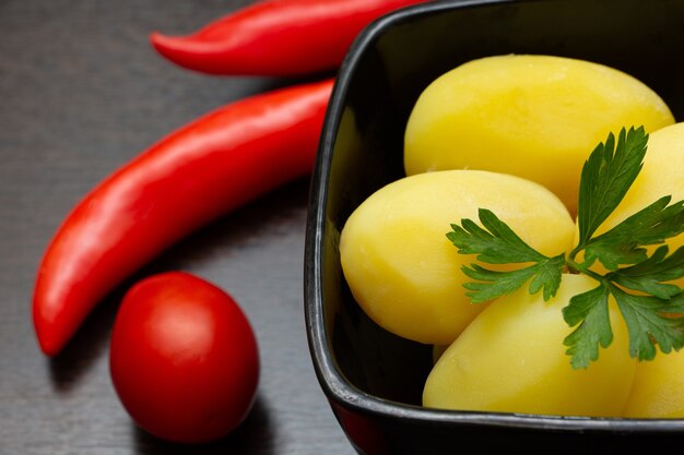 Gotowane ziemniaki z papryczką chili i pomidorami na ciemnym tle