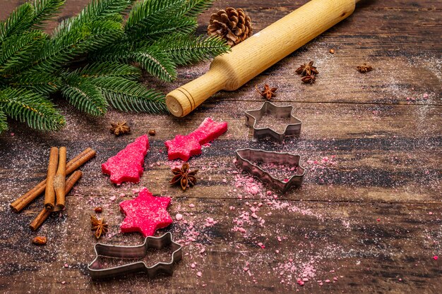 Gotowanie czerwonych ciasteczek imbirowych. Tradycyjne świąteczne wypieki. Jodła, przyprawy, foremki do ciastek, surowe ciasto, wałek do ciasta, deski drewniane