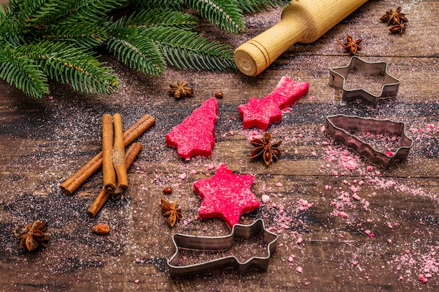 Gotowanie czerwonych ciasteczek imbirowych. Tradycyjne świąteczne wypieki. Jodła, przyprawy, foremki do ciastek, surowe ciasto, wałek do ciasta, deski drewniane