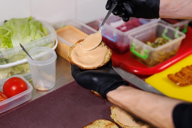 Zdjęcie gotowanie hamburgera na grillu rozrzucanie sosu na bułeczkę hamburgerową