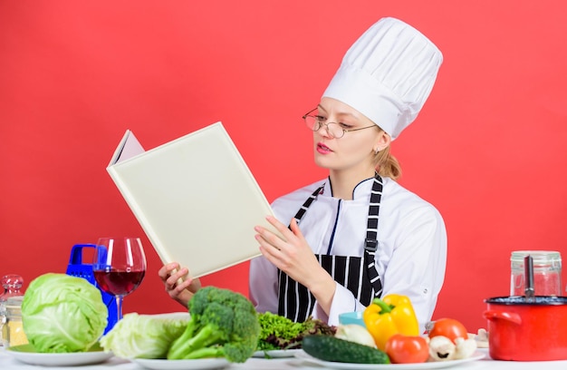 Zdjęcie gotowanie i serwowanie zdrowego wegetariańskiego menu ładna kobieta kucharz czyta kartę menu przy kuchennym stole urocza kobieta uczy się menu restauracji na jeden dzień lista dań i napojów w menu