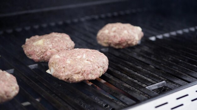 Gotowanie kotletów wołowych z hamburgerami na grillu gazowym.