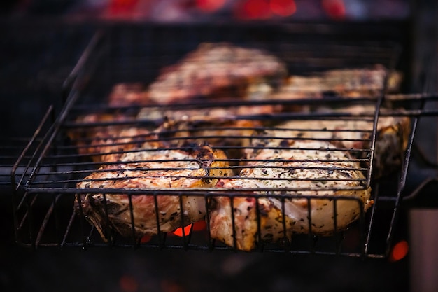 gotowanie na łonie natury, w grillu spalanie węgli, na których na ruszcie smażone są duże kawałki mięsa