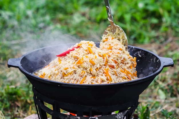 Gotowanie pilawu ryżowego w dużym garnku żeliwnym w ogniu