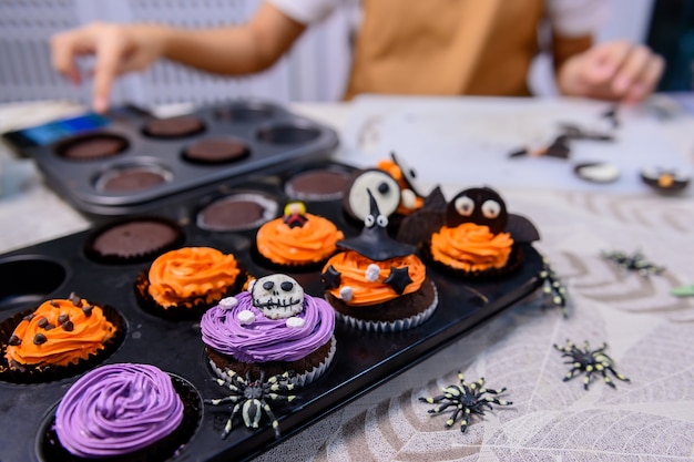 Zdjęcie gotowanie pysznego domowego ciasta i dekorowanie babeczki na świąteczny halloween. przygotowanie i mieszanie składników na słodki deser spożywczy w kuchni w domu.