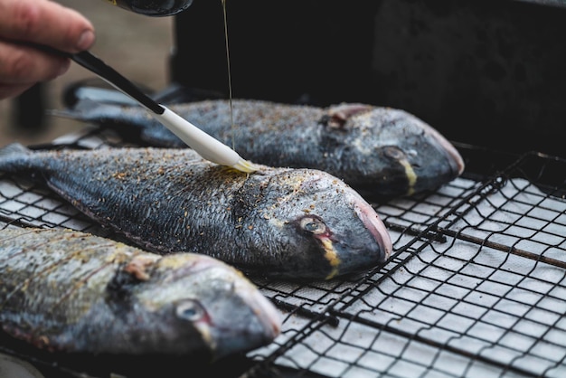 Gotowanie ryby morskiej surowej ryby dorado z przyprawami na siatce BBQ