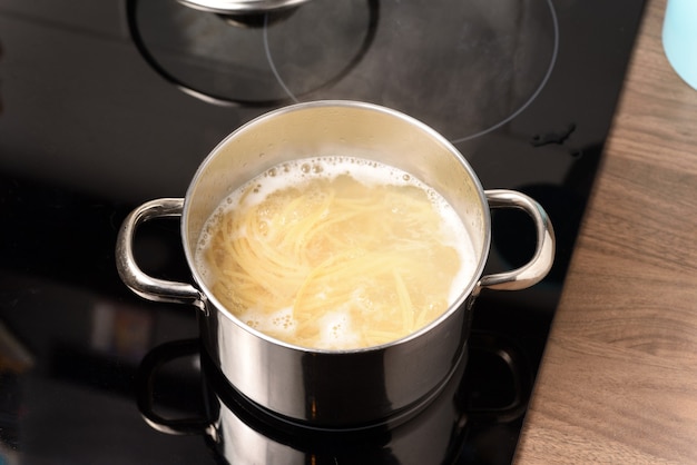 Gotowanie spaghetti w rondlu na kuchence elektrycznej.