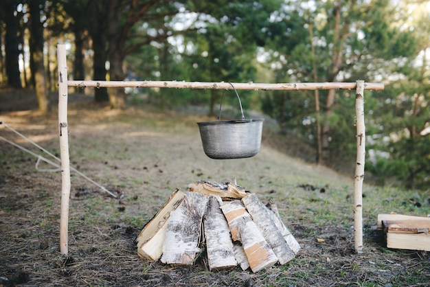 Zdjęcie gotowanie w warunkach polowych, gotowanie garnka przy ognisku na pikniku. filtrowany obraz: efekt vintage poddany obróbce krzyżowej.