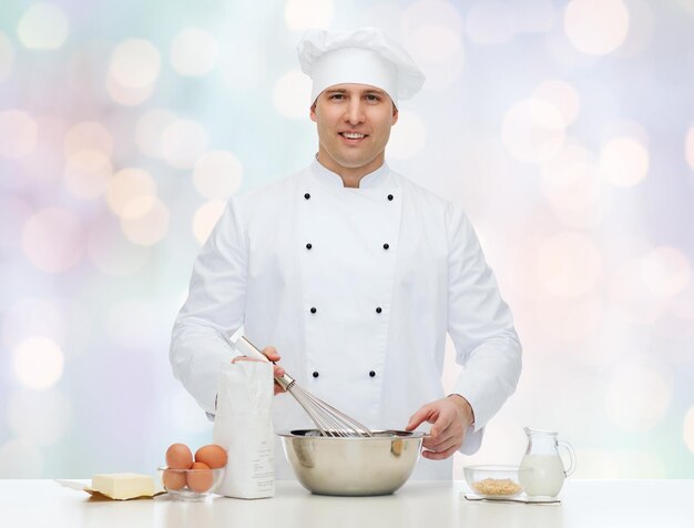 gotowanie, zawód, haute cuisine, jedzenie i koncepcja ludzi - szczęśliwy mężczyzna kucharz kucharz pieczenia na niebieskim tle światła