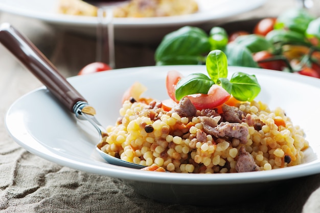 Gotowany sardyński makaron fregola z pomidorem i kiełbasą