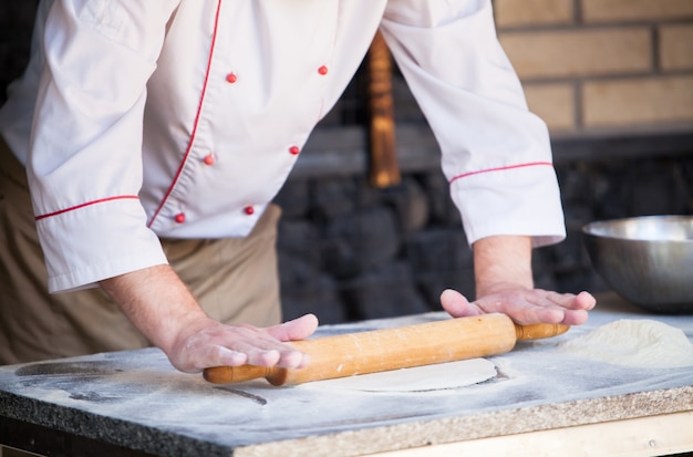 Zdjęcie gotuj przygotowywanie pizzy w restauracji.