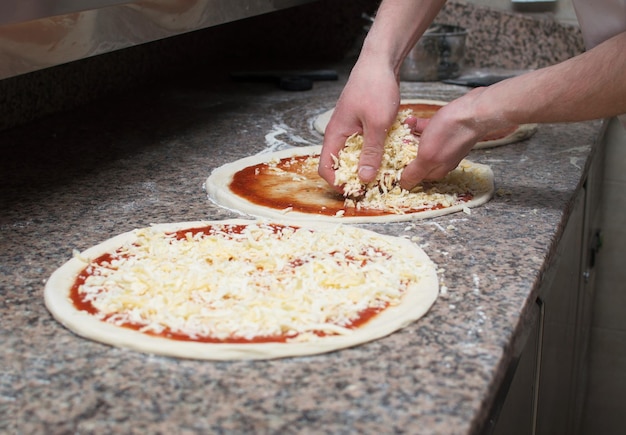 Gotuj w kuchni, umieszczając składniki na pizzy Koncepcja pizzy