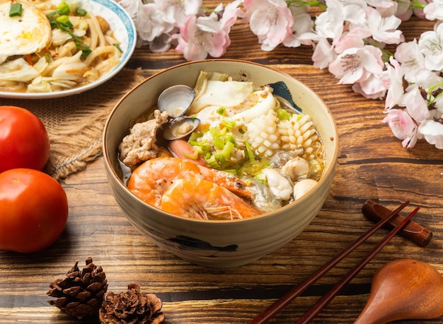 Gout Hot Pot Noodles z pomidorami i pałeczkami podawany w naczyniu na drewnianym stole z widokiem na chińskie jedzenie