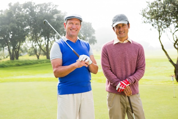 Gra w golfa przyjaciele uśmiecha się do kamery gospodarstwa klubów