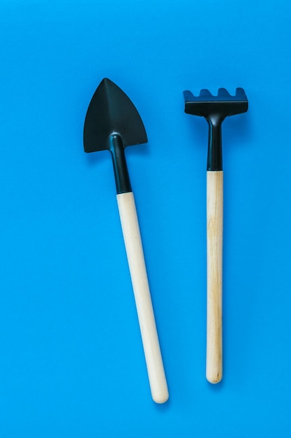 Zdjęcie grabie i łopata do uprawy gleby na niebieskim tle narzędzie do pracy z roślinami domowymi i ogrodowymi