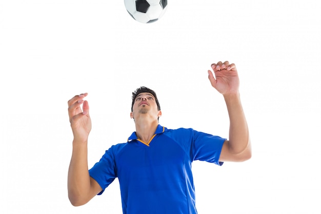 Gracz futbolu w błękitnym doskakiwaniu piłka