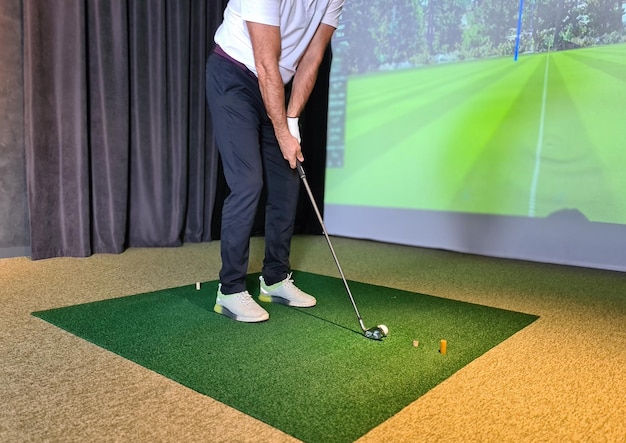 Gracz w golfa grający w golfa w pomieszczeniu na symulatorze golfa