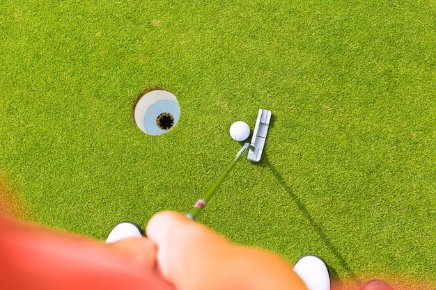 Gracza golfa kładzenia piłka w dziurze