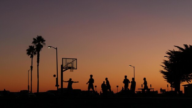 Gracze na boisku do koszykówki grający w koszykówkę, zachód słońca na plaży w Kalifornii