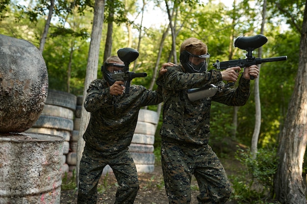 Zdjęcie gracze paintballa w mundurach i maskach w lesie