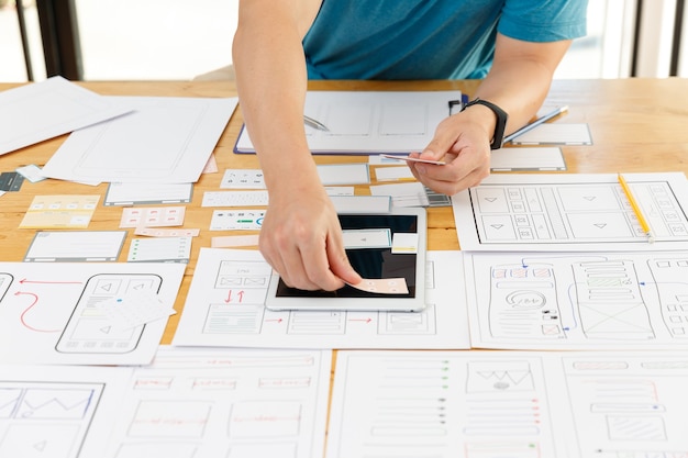 Graficy współpracują z projektantem UX UI, który planuje szablon układu aplikacji na telefon komórkowy komputer mobilny