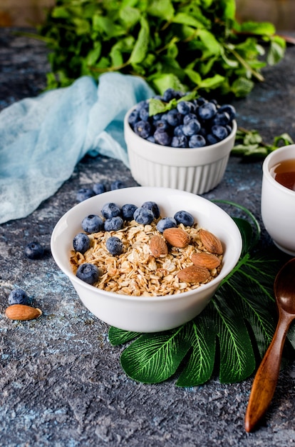 Granola Z Jagodami Na Białym Talerzu I Filiżanką Herbaty Na śniadanie, Domowe Pieczone Muesli Z Orzechami I Miodem Dla Małej Słodyczy.